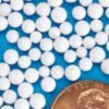 Close-up picture of EPS Expanded Polystyrene beads nest to a penny to show size