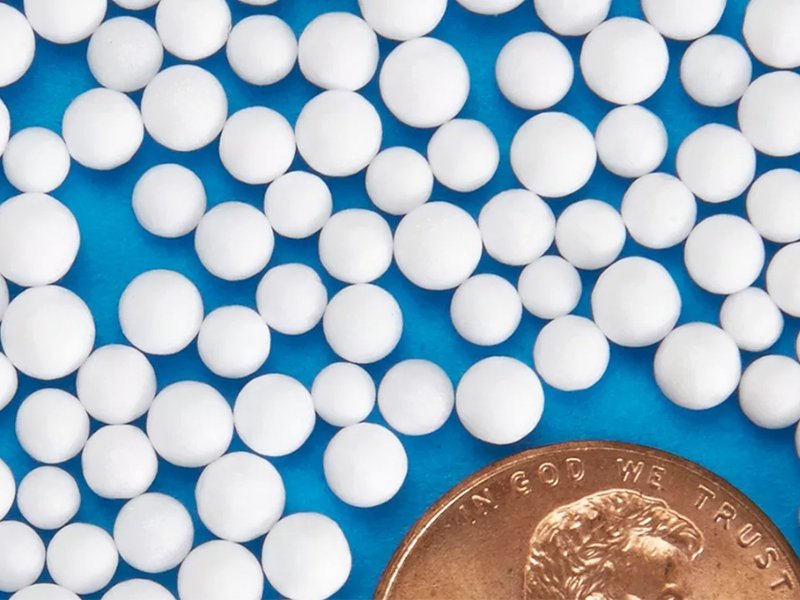Close-up picture of EPS Expanded Polystyrene beads nest to a penny to show size