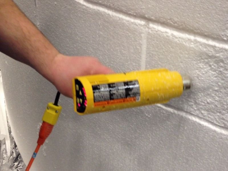 Heat gun is melting Styrofoam expanded polystyrene EPS foam to make it look like stone blocks