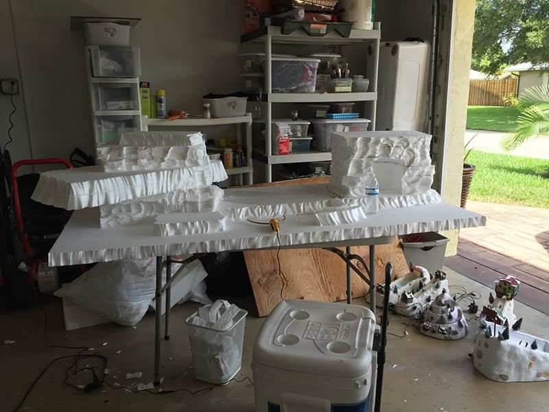 Making scenery for a winter village from pieces of Styrofoam on top of a table