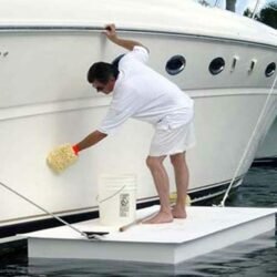 Man stands on floating EPS expanded polystyrene Styrofoam platform cleaning a boat