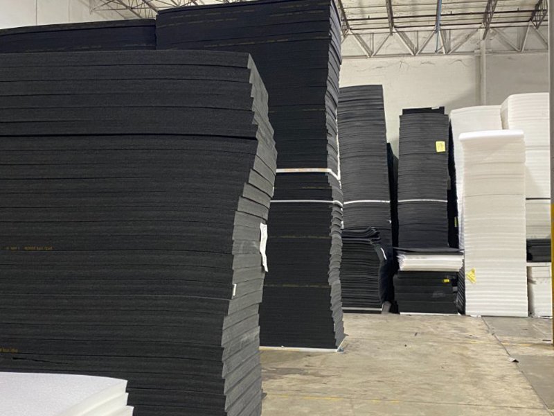 Sheets of cross-linked XLPE foam sheets in charcoal gray and black colors in a wholesale warehouse